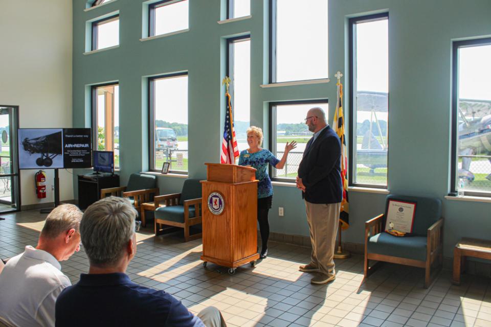 Nancy LaJoice, Senior Business Development Representative of the Maryland Department of Commerce, offers remarks. Right outside the window sits a Boeing Stearman, owned and operated by Captain Hunter Harris that was built in 1942, the same year the Easton
