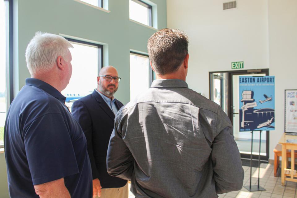 Airport business professionals overlook the Easton Airport 80th Anniversary artwork.